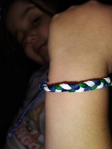 Close-up of a customer's wrist wearing the woven DAVID Bracelet in blue, green, and white.
