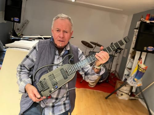 Ein Kunde hält die kompakte, graue Donner HUSH™ X PRO Multi-Effekt-E-Gitarre in einem Raum.