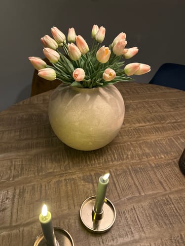 Recensent toont het Oud Roze Tulpen Boeket in een ronde vaas op een houten tafel.