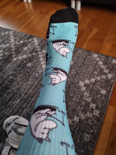 Recensents fot som bär en turkos Mumin Stödstrumpa med muminmönster.