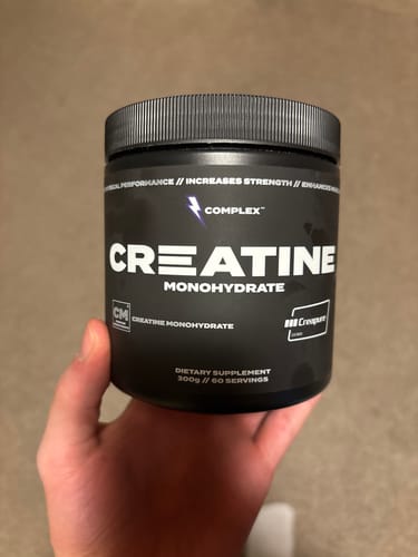 Reviewer holding a black tub of Complex Creapure Creatine Monohydrate.