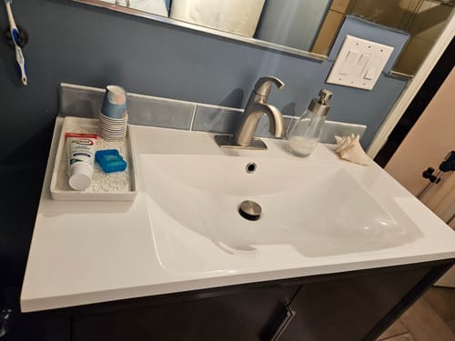 Customer's bathroom showing the dark blue paint on the wall above the sink, which matches the grey backsplash tiles.