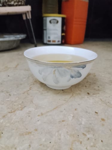 Reviewer's intact English Porcelain Tea Cup with a floral design, filled with liquid on a countertop.