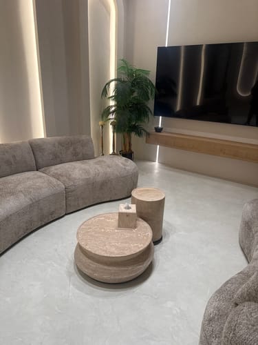 Customer's Nimbus Travertine Small Side Table placed next to a curved sofa in a modern living room.
