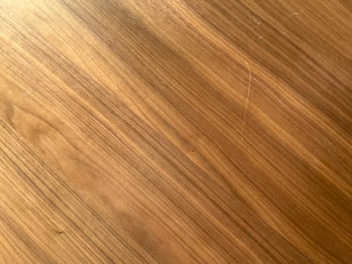 Detailopname door een recensent van het walnoot tafelblad van de Evolve eettafel, waarop krassen zichtbaar zijn.