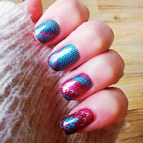Nahaufnahme der Nägel einer Kundin mit den True Love's Bouquet Nagelfolien in einem glänzenden, pink-blauen Strickdesign.