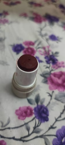 Reviewer's open VELVET FLUSH blush stick showing the maroon-colored product in its white tube.