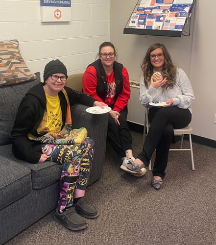 Reviewer sitting indoors with two other people, wearing the light-colored Sense & Sensibility Sweater.