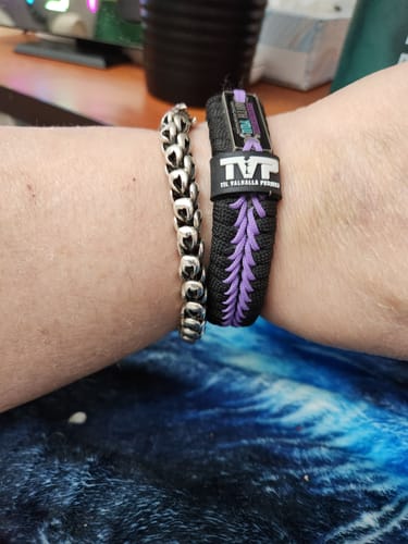 Customer wearing the black and purple You Belong Here paracord bracelet on their wrist next to another bracelet.