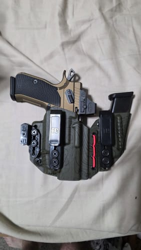 Customer's dark green AXIS ELITE holster holding a tan pistol and an extra magazine on a light-colored surface.
