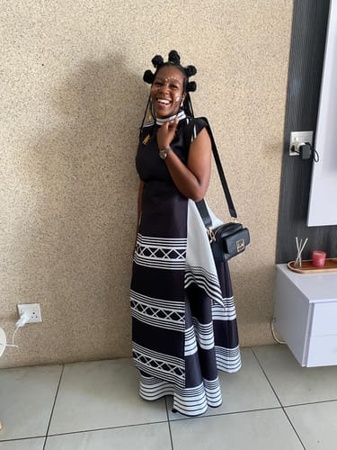 Customer smiling while wearing the black and white Printed Short Sleeve Xhosa Two Piece Set indoors.