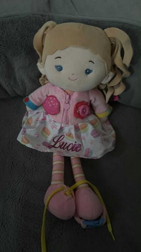 Customer's Personalized Cupcake Girl doll, embroidered with the name 'Lucie' on its dessert-themed dress, sitting on a couch.