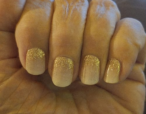 Hand eines Kunden mit den aufgetragenen 'Babyboomer Nude Sparkle' UV-Gelfolien. Die kurzen Nägel haben einen glitzernden Nude-Farbverlauf.