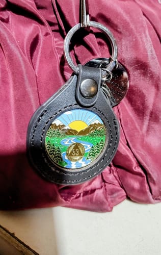 Customer's dark leather medallion keychain holder displaying a colorful AA recovery chip.