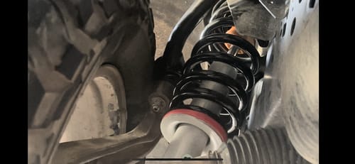 Customer's close-up view of the installed Upper Control Arms behind the black coil spring on their Ford truck.