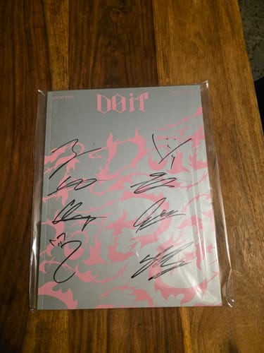 Customer's autographed Stray Kids 'DO IT' promo album, still sealed in plastic wrap, on a wooden surface.