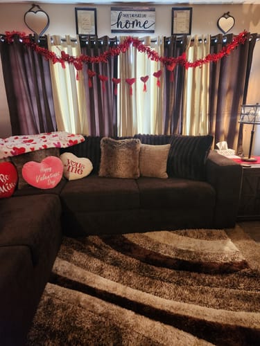 Customer's 'No Place Like Home' sign hanging in their living room above a window decorated with a red garland.