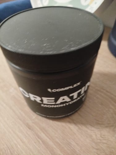Customer's black tub of Complex Creapure Creatine sitting on a wooden surface.