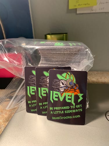 Reviewer's custom stickers with a 'LEVEL 3' skull design, with a few standing in front of a large stack.