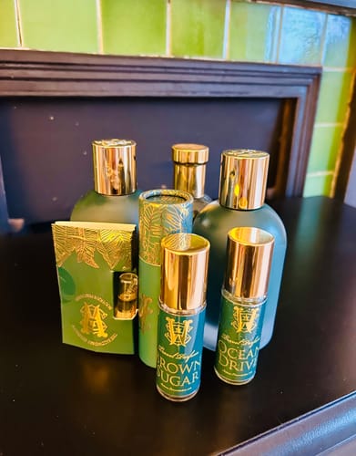 Reviewer's collection of green and gold perfumes from the same brand on a dark shelf.