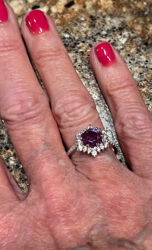 Close-up of a customer wearing the Serelith ring with its purple hexagonal stone and halo.