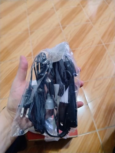 Reseñador sosteniendo una bolsa con accesorios del kit de corte de pelo Remington, incluyendo el cable y cepillos.