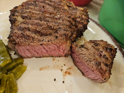 Primer plano del New York con Hueso Steak de un cliente, cortado para mostrar el término medio.