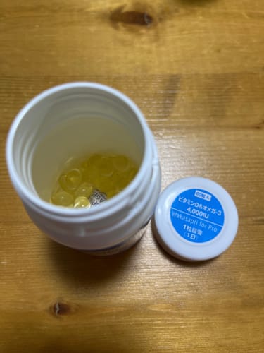 レビュー投稿者が開けた「高濃度ビタミンD＆オメガ-3」のボトル。黄色いソフトカプセルが中に入っており、隣に蓋が置かれている。