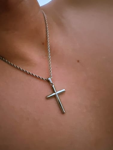 Primer plano del Crucifix Pendant plateado de un cliente, usado en el cuello con una cadena de cuerda.