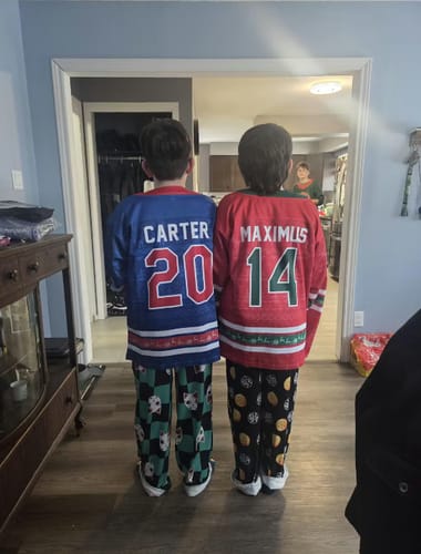 Customer's two children showing the back of their personalized blue and red Family Christmas Custom Hockey Jerseys.