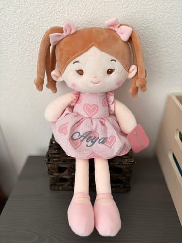 Customer's Personalized Sweetheart Girl doll sitting on a basket, with the name 'Anya' on her pink dress.