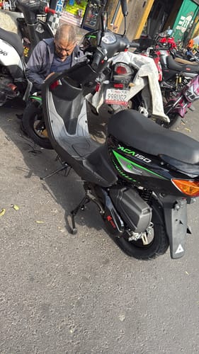 Cliente con su Motocicleta Acapulco Kiwo 150 negra estacionada en una calle junto a otras motos.