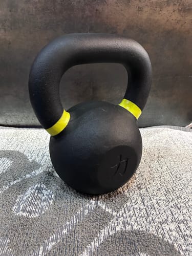 Customer's black cast iron kettlebell with yellow bands on the handle, shown up close.