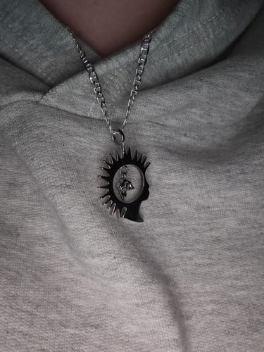 A customer wearing the silver Head in the Clouds Pendant on a chain against a grey hoodie.