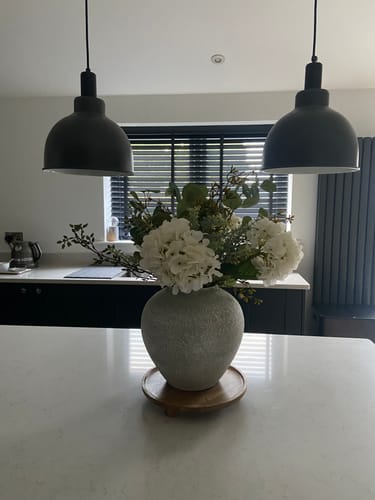 Reviewer's Arina Vase shown from a side angle on a kitchen counter, under two large pendant lights.
