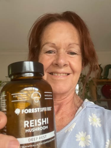 Reviewer smiling while holding a bottle of Australian Grown Reishi Mushroom Capsules.