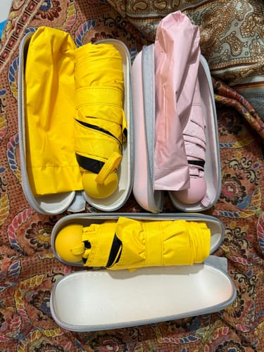 Customer's three pocket folding umbrellas, two yellow and one pink, displayed with their compact cases.