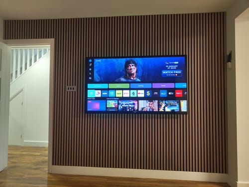 Customer's installed Natural Oak Acoustic Wall Panels creating a stylish media wall behind a mounted television.