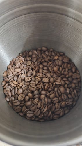 Customer's close-up view of Golden Cup Blend coffee beans in a silver canister.