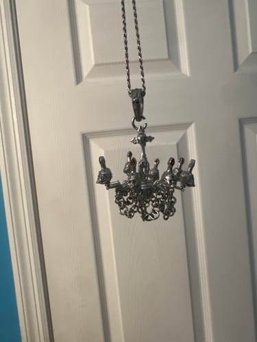 Customer's silver Chandelier Pendant with detailed skulls and chains hanging from a necklace.