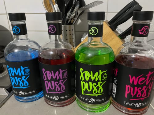 Customer's Blue Rasp 700ml bottle displayed with three other colorful liqueur bottles on a counter.