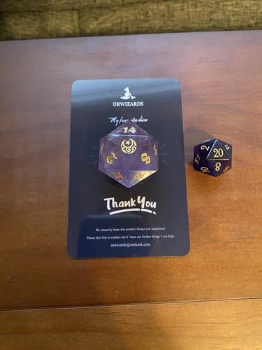 Reviewer showing the large size of the Amethyst D20 compared to a standard die.