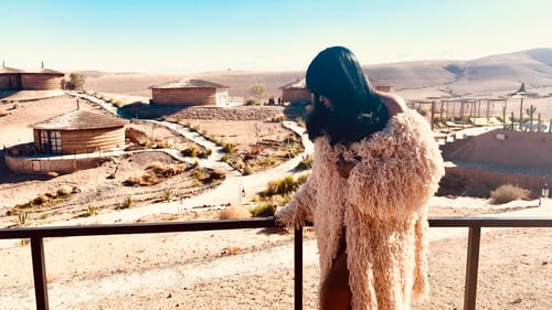 Reviewer leaning on a balcony railing, showing the texture of the Knit Shaggy Loop Coat in the sun.