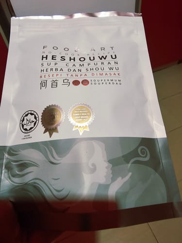 Customer holding the white and grey pouch of HESHOUWU soup from their purchase.