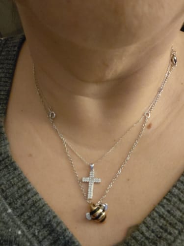 Close-up of a customer wearing the Adopt a Bee® Necklace with a bee pendant, layered with another silver necklace.
