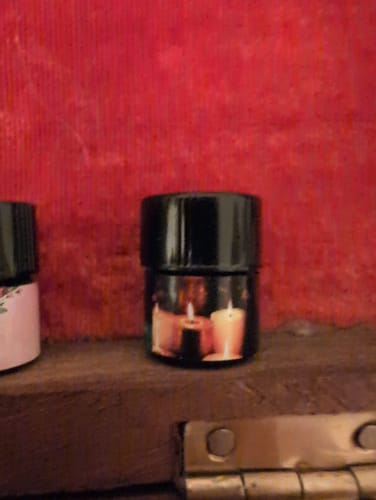 Close-up: Customer's small black jar of 'Fall In Love Whenever You Can' on a wooden shelf.
