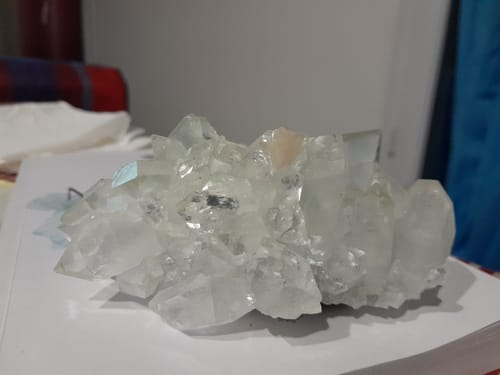 Le cristal d'Apophyllite d'un client, un amas de cristaux clairs et transparents sur une surface.