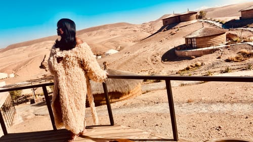 Customer wearing the shaggy Knit Shaggy Loop Coat while looking out from a balcony in a desert setting.
