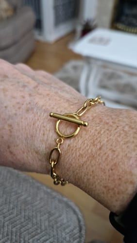 A customer's wrist with the gold Link Chain Bracelet fastened with a T-bar clasp.