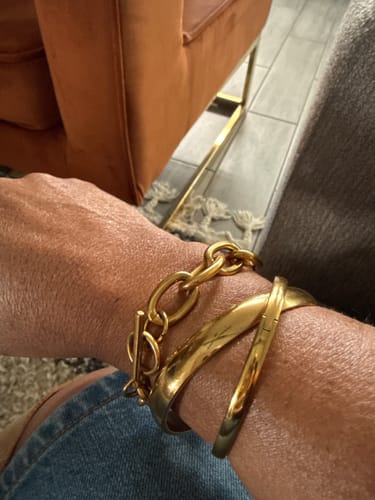 Customer's wrist showing two gold Marbella Cuff Bracelets stacked with a chain bracelet.